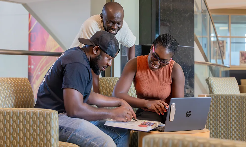SIU Students working over a textbook and computer